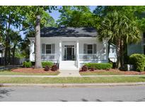 Charming home featuring a welcoming front porch and well-maintained landscaping with lush greenery and mature trees at 1040 Barfield St, Daniel Island, SC 29492