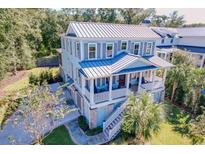 Stunning coastal home features a metal roof, shutters, and a welcoming front porch with stairs leading to a lush yard at 1212 Clonmel Pl, Mount Pleasant, SC 29464
