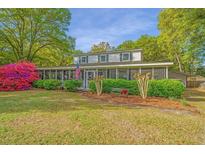 Charming two-story home with a screened-in porch and beautifully landscaped front yard with colorful flowers at 1518 Southwick Dr, Johns Island, SC 29455