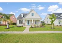 Charming single-story home featuring a manicured lawn, light beige siding, and a bright turquoise front door at 154 Helena Park Dr, Summerville, SC 29486