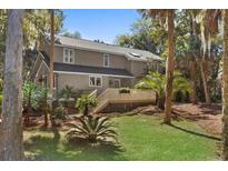 Charming two-story home featuring a well-maintained lawn, mature trees, and a spacious deck at 3510 Deer Run Rd, Seabrook Island, SC 29455
