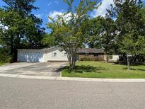 Charming single-story home featuring a well-manicured lawn and mature trees at 411 Navaho Cir, Summerville, SC 29483