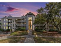 Stunning condominium building featuring multiple stories and private balconies with lush landscaping and walkway at 9000 Palmetto Dr # 202-C, Isle of Palms, SC 29451