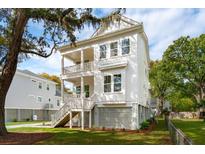 Charming two-story white home featuring double porches, a manicured lawn, and mature trees at 1409 Lieben Rd, Mount Pleasant, SC 29466