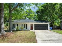 Charming single-story home featuring a red front door, gray garage door, and mature trees at 1812 Overrun St, Charleston, SC 29414