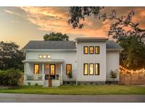 Inviting two-story home with white siding and a cozy front porch basking under a beautiful sunset at 2 Live Oak Ave, Charleston, SC 29407