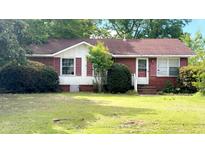 Cozy one-story brick home featuring red shutters, a classic design, and mature landscaping at 3293 Stonehaven Dr, North Charleston, SC 29420
