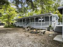 Inviting home featuring a cozy fire pit with stone benches and a spacious, covered front porch at 4869 Slans Island Rd, Hollywood, SC 29449