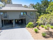 Exterior view of a two-story home with a driveway, landscaping, and a view of the surrounding trees at 754 Summerwind Cir, Edisto Island, SC 29438