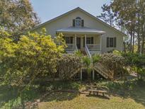 Charming two-story home with a metal roof, inviting front porch and lush landscaping at 8551 Pope Landing Rd, Edisto Island, SC 29438