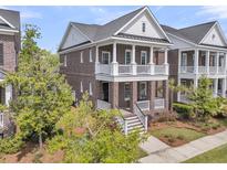 Charming two-story brick home with double front porches, white railings, and manicured landscaping at 112 Brailsford St, Charleston, SC 29492