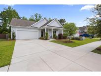 Charming single-story home features a well-manicured lawn, a two-car garage, and inviting front porch at 1513 Thin Pine Dr, Johns Island, SC 29455
