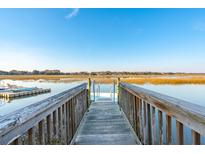 Scenic wooden dock leading to calm water and marshland under a clear blue sky at 1614 Teal Marsh Rd, Charleston, SC 29412