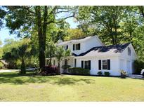 Charming two-story white home with black shutters surrounded by lush greenery and a well-manicured lawn at 212 Blue Heron Dr, Summerville, SC 29485