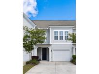 Charming townhome features a single-car garage, dark front door, manicured lawn, and beautiful landscaping at 2308 Watchtower Ln, Charleston, SC 29414