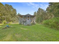 Charming two-story home with a covered front porch, steps, and a lush green lawn at 364 Dupre Rd, McClellanville, SC 29458