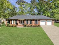 Charming single story brick home featuring an attached two car garage and lush green lawn at 411 Red Fox Run, Summerville, SC 29485