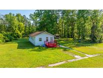 Charming cottage-style home with red deck, surrounded by lush greenery and a well-maintained lawn at 11341 Cottageville Hwy, Cottageville, SC 29435