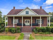 Charming brick home featuring a covered porch, manicured lawn, and classic architectural details at 200 Broughton Rd, Moncks Corner, SC 29461