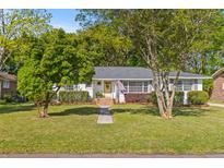 Charming home with a well-manicured lawn, mature trees, and a welcoming yellow front door at 405 Cross St, Charleston, SC 29407
