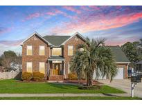 Charming two-story brick home with a lush green lawn and mature landscaping under a beautiful sky at 406 King Charles Cir, Summerville, SC 29485