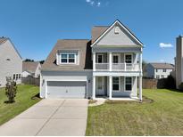 Charming two-story home with a double front porch, well-maintained lawn and a two car garage at 514 Morelets Dr, Moncks Corner, SC 29461