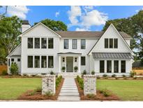 Striking two-story home with crisp white siding, black trim windows, and inviting front yard with brick detail at 924 Trowman Ln, Mount Pleasant, SC 29464