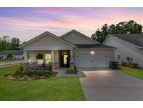 Charming single-story home boasts a manicured lawn and inviting front porch, complete with stone accents at 1003 Locals St, Summerville, SC 29485