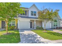 Charming townhome showcases a manicured lawn, and a paved driveway leading to an attached garage at 131 Buchanan Cir, Goose Creek, SC 29445