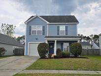 Charming two-story home with light-blue siding, a well-manicured lawn, and a driveway leading to an attached garage at 328 Bradley Bend Dr, Moncks Corner, SC 29461