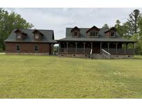 Charming log cabin with a covered porch and well-maintained lawn, perfect for country living at 3936 Lodge Hwy, Smoaks, SC 29481