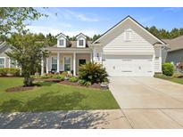 Charming white home features manicured lawn, beautiful landscaping, and attached two-car garage at 559 Eastern Isle Ave, Summerville, SC 29486