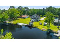 Expansive waterfront property with a well-maintained lawn, private dock, and cozy green home at 643 Backfield Rd, Walterboro, SC 29488
