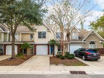 Townhomes featuring attached garages, well-maintained landscaping, and brick accents at 8679 Grassy Oak Trl, North Charleston, SC 29420