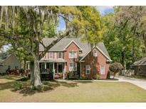 Charming two-story brick home featuring a well-manicured lawn, mature trees, and welcoming front porch at 8781 Laurel Grove Ln, North Charleston, SC 29420