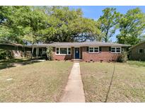 Charming brick home featuring a manicured front lawn and a walkway leading to a blue front door at 1142 Camden St, North Charleston, SC 29405