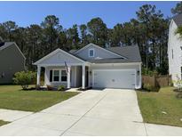 Charming single-story home featuring a two-car garage, manicured lawn, and inviting front porch at 117 Camellia Bloom Dr, Moncks Corner, SC 29461