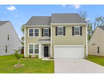 Charming two-story home with a well-manicured lawn and attached two-car garage at 1728 Refuge Dr, Ladson, SC 29456