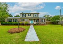 Charming two-story home featuring manicured lawn, neat landscaping, and an inviting light blue front door at 310 Land O Pines Cir, Moncks Corner, SC 29461