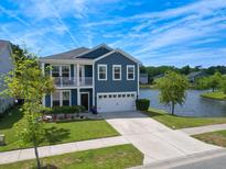 Charming two-story home features a balcony, well-manicured lawn, and waterfront views with a two car garage at 3149 Timberline Dr, Johns Island, SC 29455