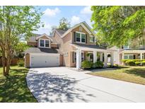 Inviting two-story home featuring a spacious front porch and a well-manicured lawn with mature trees at 5471 Rising Tide, North Charleston, SC 29420