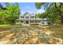 Charming two-story home with a large front porch and well-manicured lawn surrounded by mature trees at 5950 Kelseys Mill Rd, Ravenel, SC 29470
