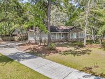 Charming single-story home with a brick facade, surrounded by mature trees and a well-manicured lawn at 106 Spring Farm Pl, Summerville, SC 29485