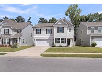 Charming two-story home with a manicured lawn, attached garage and inviting front porch with dark door at 1167 Mossy Rock Dr, Summerville, SC 29485