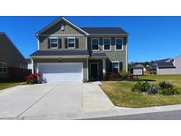 Charming two-story home featuring a two-car garage, manicured lawn, and vibrant flower beds adding curb appeal at 167 Cypress Plantation Rd, Moncks Corner, SC 29461