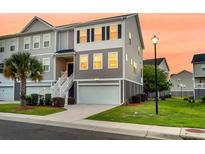 Charming townhome with a two-car garage, manicured lawn, and inviting staircase leading to the front entrance at 207 Winding River Dr, Johns Island, SC 29455