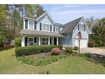 Charming two-story home with an American flag, well-maintained lawn, black shutters, and inviting front porch at 8566 Royal Palm Ln, North Charleston, SC 29420