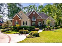 Beautiful brick and stucco home with lush landscaping and a welcoming front entrance at 8642 W Fairway Woods Dr, North Charleston, SC 29420