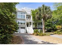 Stunning multi-level home boasting a rooftop deck, complemented by a lush front yard with mature palms and trees at 9 24Th Ave, Isle of Palms, SC 29451