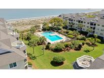 Stunning aerial view of a resort-style community with a pool, lush landscaping, and direct beach access at 9000 Palmetto Drive # D-304, Isle of Palms, SC 29451